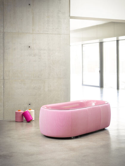 Großer heller Raum mit Betonwänden, in dem eine rosa Badewanne von Bette mit Funktionsstoff steht.