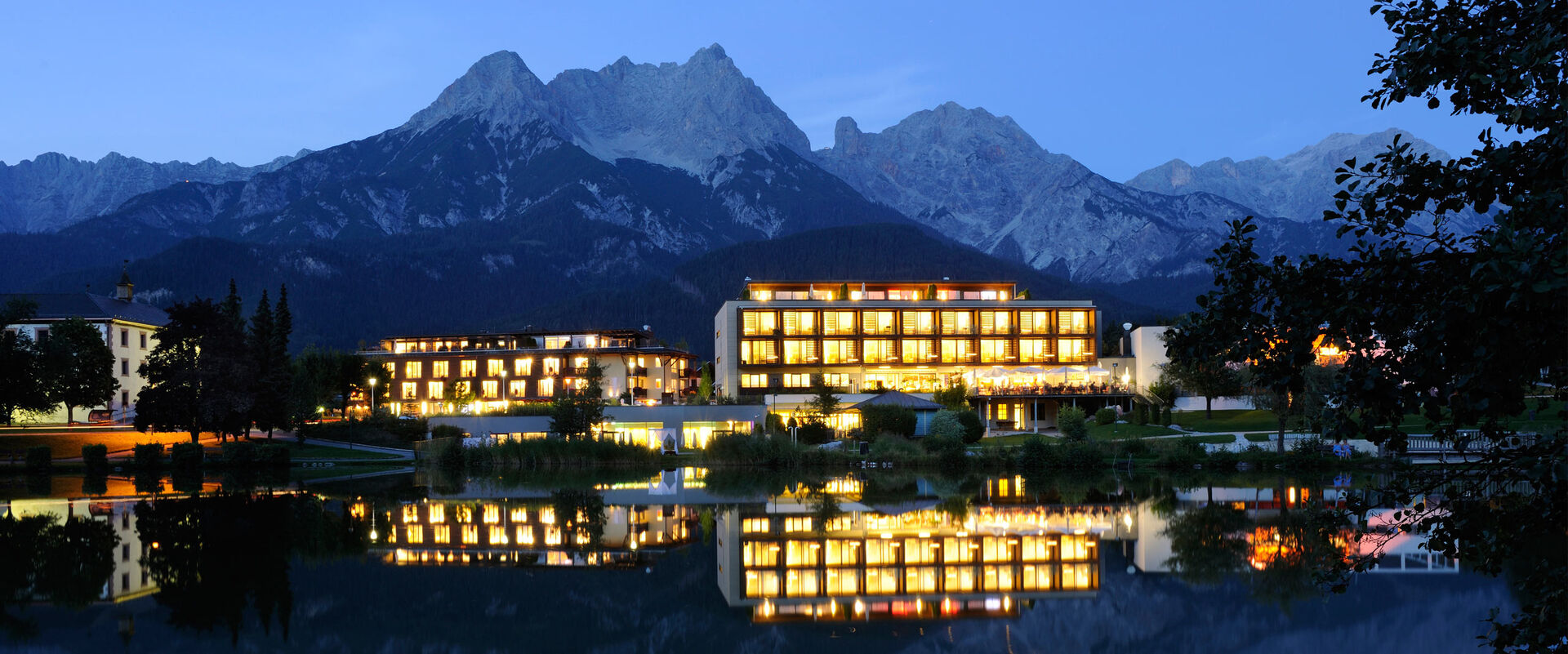 Aussenansicht des Hotel Ritzenhof am Abend mit Beleuchtung. Berge im Hintergrund.