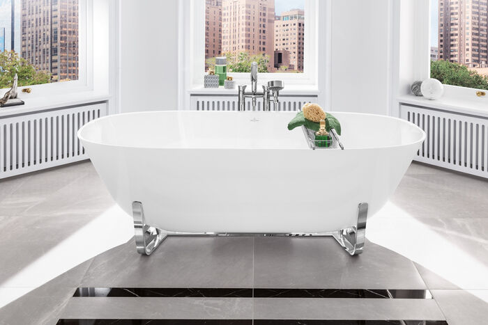 Ovale freistehende Badewanne weiss mittig im Raum auf Chromfüßen.