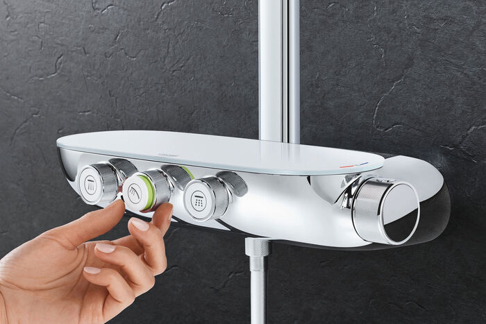 Nahaufnahme der GROHE Smartcontrol Duscharmatur. Es sind insgesamt vier verschiedene Betätigungsknöpfe mit unterschiedlichen Funktionen angebracht. Eine Hand betätigt den mittleren Betätigungsknopf auf der vorderen Seite.