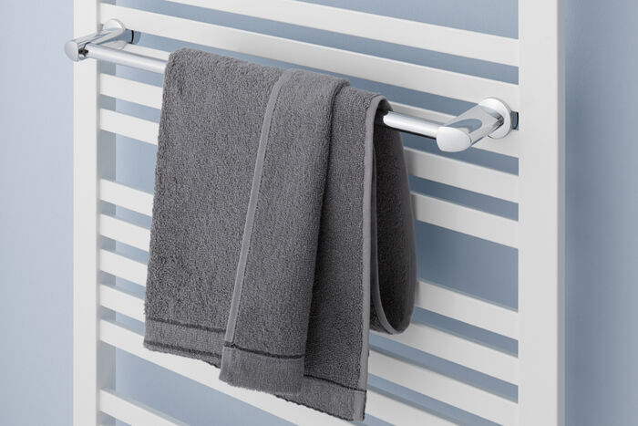 Handtuchhalterreeling an Badheizkörper montiert mit grauem Handtuch.