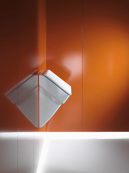 Wandmontiertes Urinal weiß auf Wand in orange.