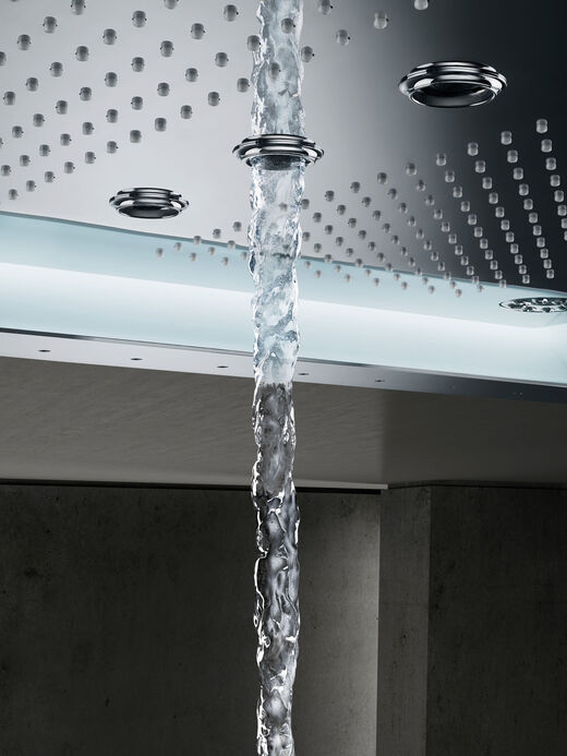 Nahaufnahme der GROHE Aqua Symphony Rainfall Regendusche. Es sind unterschiedliche Düsenformationen zu erkennen. Aus einer größeren Düse fließt aus einem dicken Strahl Wasser.