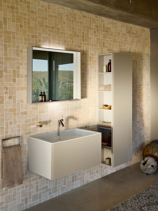 Seitliche Ansicht auf Waschplatz mit grauen Badmöbeln, Waschbeckenunterschrank mit Einsatz, wandhängender Hochschrank und Badspiegel.