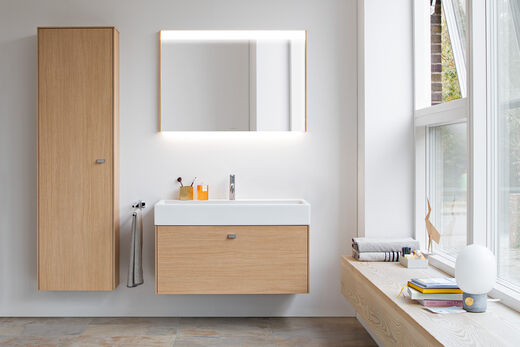 Duravit Brioso Holzbadmöbel. Hochschrank und Waschbecken mit Unterschrank und beleuchteter Spiegel.