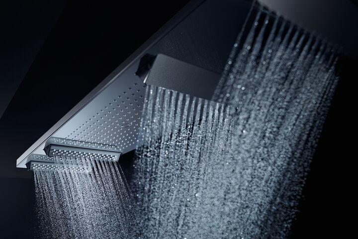 Design Duschsystem Shower Heaven von Axor. An einer rechteckigen, länglichen Kopfbrause sind mehrere zusätzliche Brausen installiert aus denen in unterschiedliche Richtungen Wasser fließt.