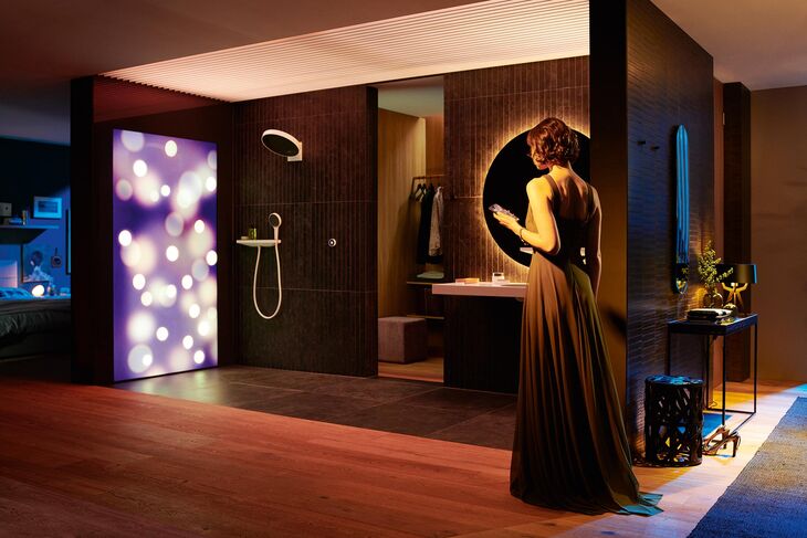 So klingt der Tag perfekt aus: Frau im langen Abendkleid betritt den mit einem RainTunes System ausgestatteten Duschbereich. Sanfte Illuminationen, Ton und Duft werden vereint.
