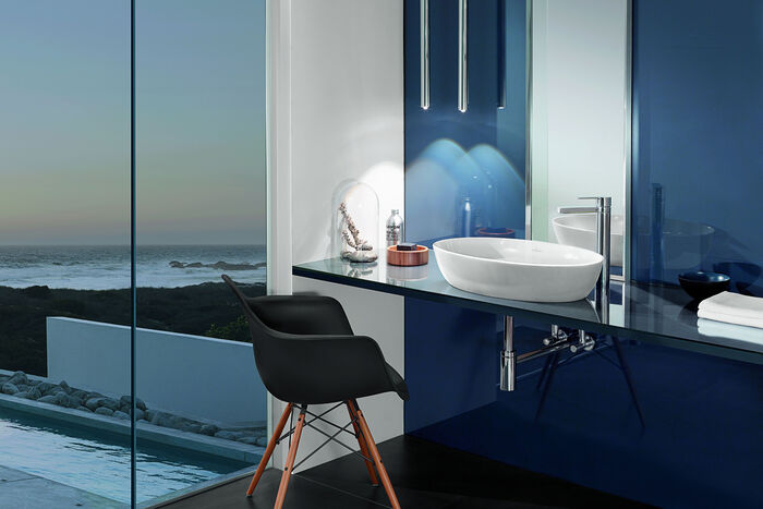 In Blautönen gehaltenes Badezimmer, auf dessen Waschtisch sich das Artis Waschbecken von Villeroy und Boch befindet. Vor dem Waschtisch steht ein Stuhl.