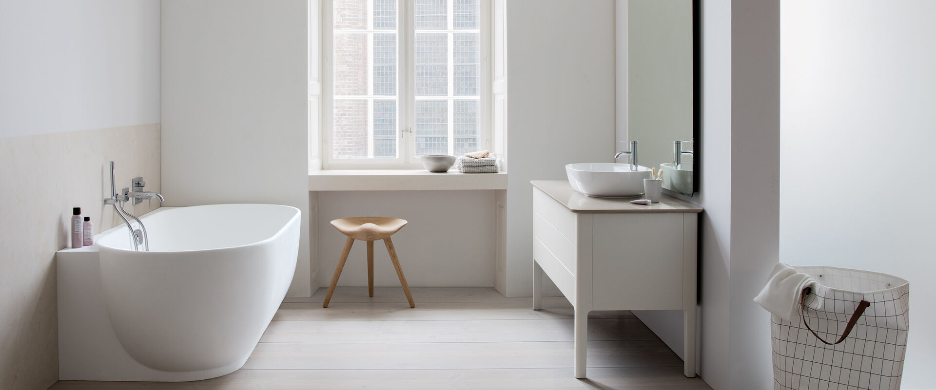 Modernes weißes Badezimmer mit Badewanne wandbündig und Waschplatz seitlich.