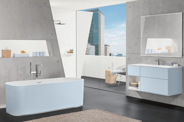 Grosses Badezimmer mit hellblauem Unterschrank und Badewanne. Loftcharakter mit Blick auf City.