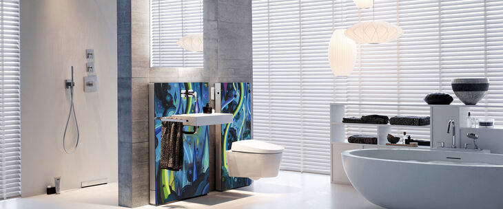 Kunst & Design vereint: Traumbadezimmer von Geberit ausgestattet mit dem praktischen Dusch-WC AquaClean Mera, Dusche, Waschplatz und Freistehwanne. Hinter dem Waschtisch und dem WC sind farbig gestaltete Kunstwände auf der Vorwandinstallation angebracht.