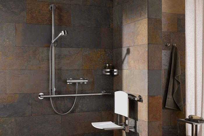 Sicher Duschen: Dusche, die mit dem Relingsystem KEUCO Plan Care ausgestattet ist. Diese Duschstange ist auch als Haltegriff geeignet. Ebenso erleichtert der Duschklappsitz mit weißem Polster von KEUCO Plan das Duschen.