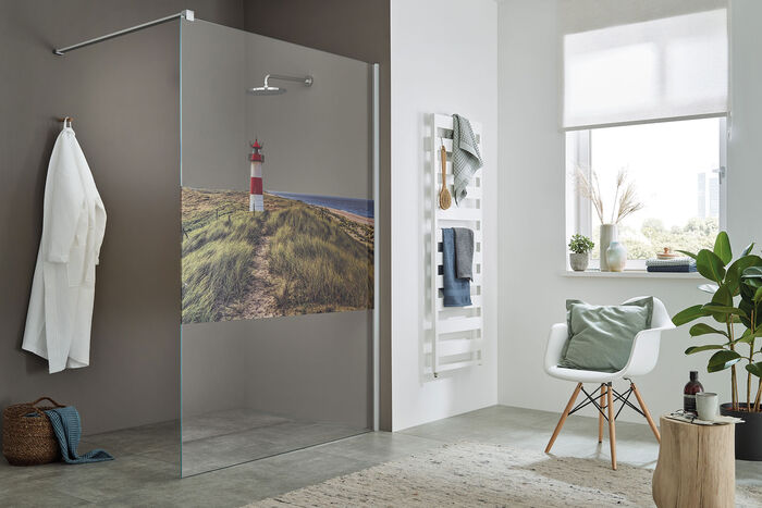 Offene Walk-in-Dusche von Sprinz aus einer stabilen Glaswand von einer Stange fix gehalten. Highlight der Serie ColorStar ist die farbige Bedruckung des Glases als Sichtschutz - hier Motiv Sylter Leuchtturm.