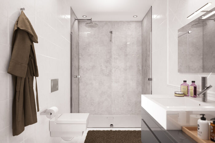 Badezimmer, in dessen Dusche eine graue Easy Style Wandverkleidung von HUEPPE angebracht ist. vor der Dusche befindet sich Links eine Toilette, daneben hängt ein Bademantel. Rechts befindet sich ein Waschbecken mit Spiegel.