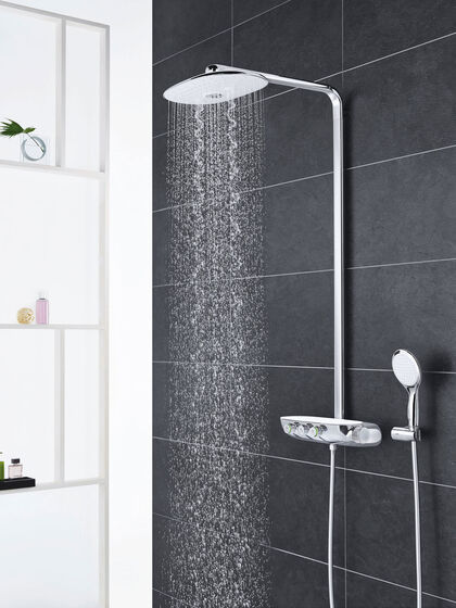 GROHE Smart Control Duscharmatur, die an einer grau gefliesten Badezimmerwand installiert ist. Angebracht sind sowohl Hand- als auch Kopfbrause. Aus der Kopfbrause fließt Wasser.