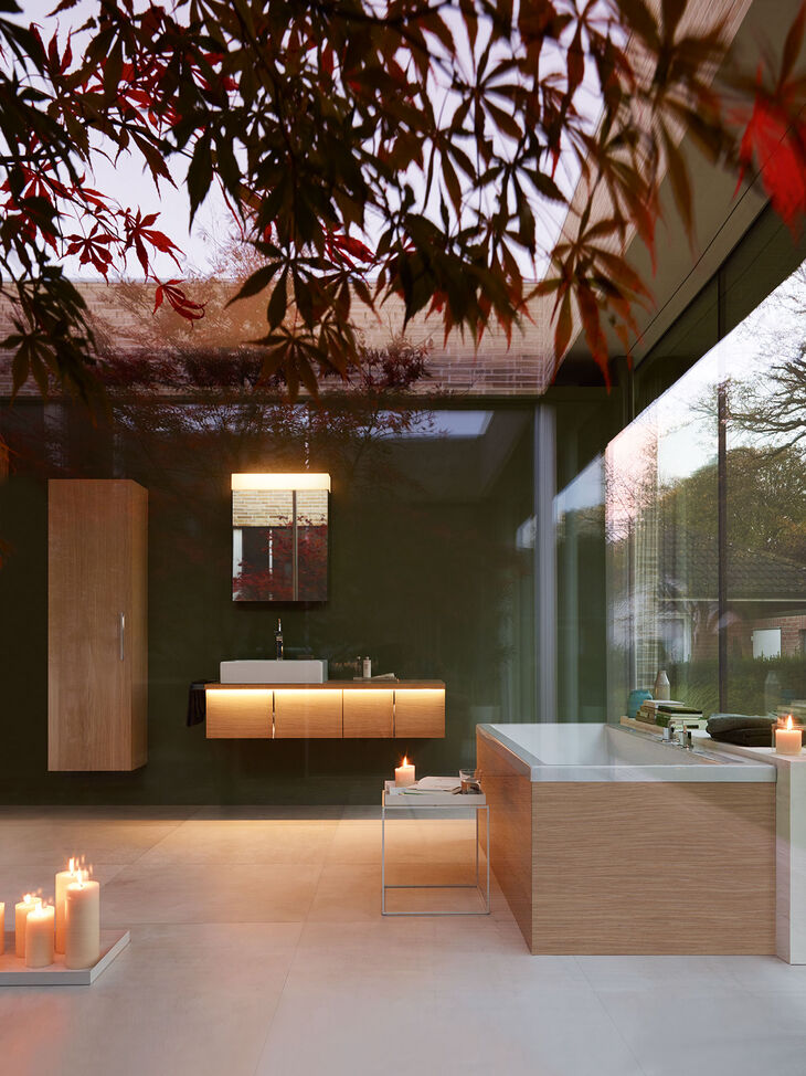 Duravit Vero Badambiente in Abendstimmung. Hochschrank, Waschbecken, beleuchtesr Unterschrank, Spiegel und Badewanne.