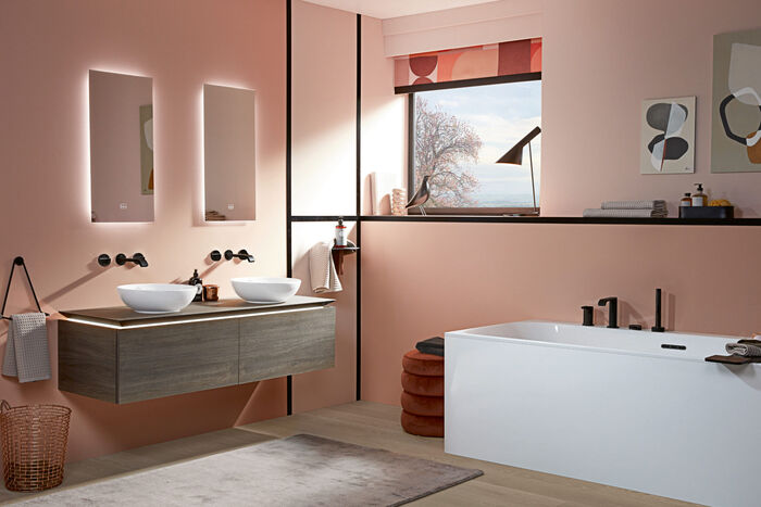 Blick in das gesamte Badezimmer in hellen, modernen Farben, ausgestattet mit der Badewanne sowie den Waschtischen der Loop & Friends Kollektion von Villeroy & Boch in Weiß mit schwarzen Armaturen. 