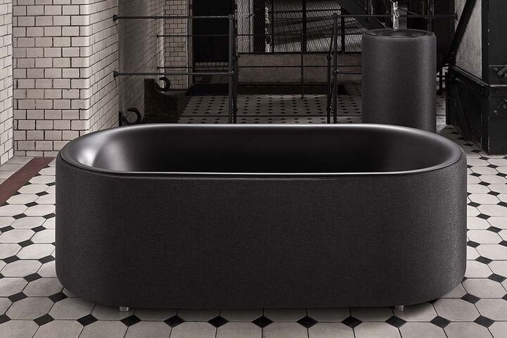 Schwarze freistehende Badewanne mit Stoffbezug. im Hintergrund das passende Waschbecken.