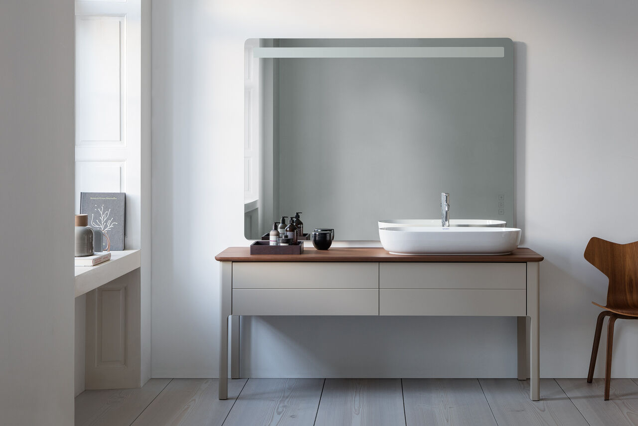 Komplettbad LUV von Duravit Graues Badmöbel aus Holz mit weißem ovalen Aufsatzwaschbecken und Badspiegel.