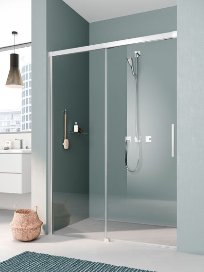Badezimmer, in dem in einer Nische eine Kermi Nica Duschkabine installiert ist. Die Wände sind grau-turkies gehalten, links befindet sich ein Waschbecken, über dem eine Lampe hängt.