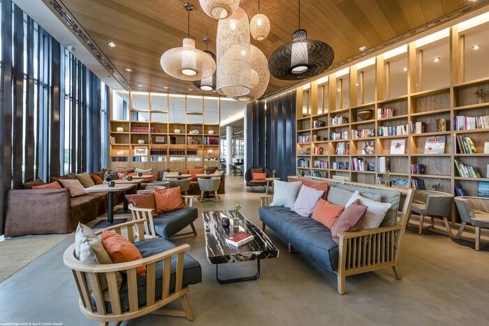 Sofa und Stühle mit bunten Kissen in der Bibliothek mit Bücherregalen der Seezeitlodge.