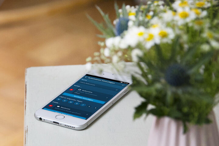 Smartphone auf einer Tischablage mit der Ansicht Steuerung für das Smart Home.
