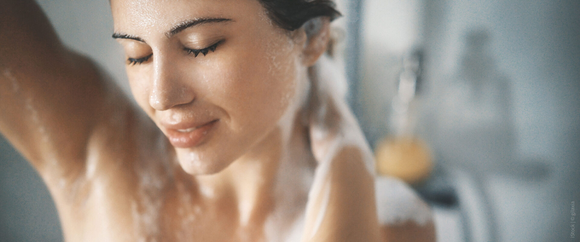 Syr Modelbild einer Frau unter der Dusche mit nassem Gesicht und Wasser.