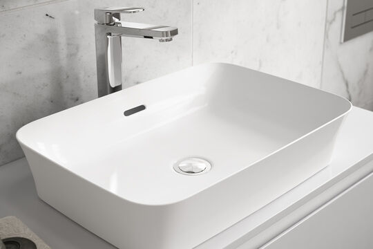 Weißes Waschbecken Ipalyss von Ideal Standard, das sich auf einem Waschtisch befindet. Darüber ist ein Wasserhahn installiert.