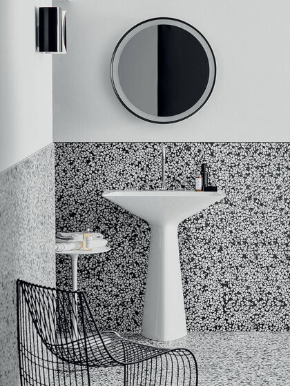 Der weiße Waschtisch Tipo-Z von Ideal Standard vor einer halbhohen gefliesten Wand aus schwarz-weißem Karomuster.