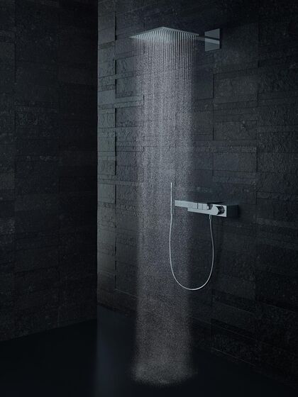Coole Duschszene in schwarz mit perlender Kopfbrause und dem edlen Thermostaten aus der Serie Edge von AXOR.