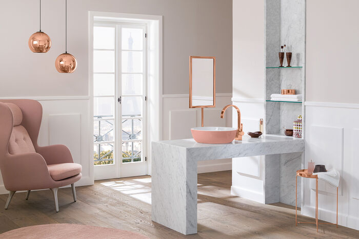 Helles Badezimmer mit Hellen Wänden und Holzfußboden. Waschtisch mit rosanem Waschbecken und Rosa Armaturen.