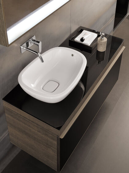 Ovales Aufsatzwaschbecken in Weiss auf brauen Badmöbeln, Unterputzarmatur chrom und beleuchteter Spiegel.