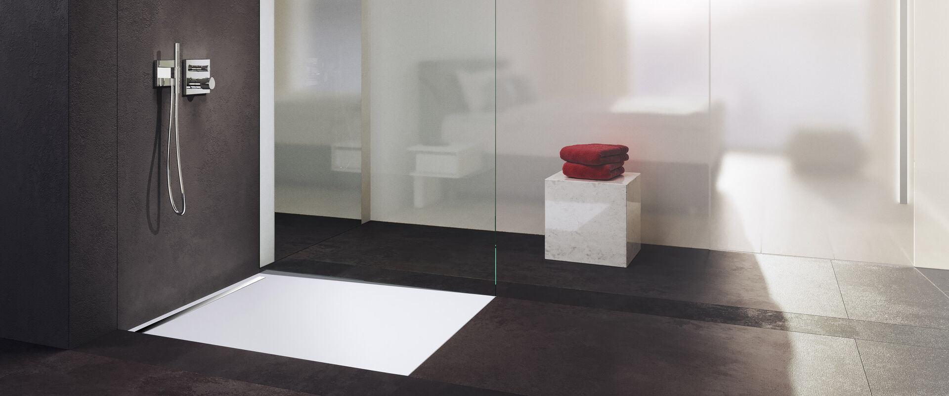 Badezimmer mit dunkelgrauem Boden und weißen sowie dunkelgrauen Wänden. In der Dusche ist eine Nexys Duschfläche von Kaldewei installiert. Im Hintergrund liegen rote Handtücher auf einem Stuhl.