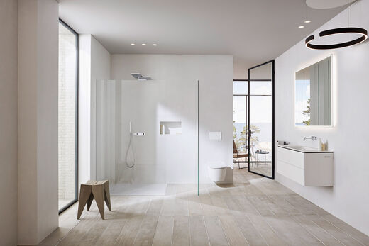 Helles, lichtdurchflutetes Badezimmer der Serie ONE von Geberit mit moderner Duschkabine ohne sichtbare Wandbefestigungen, WC und Waschbereich mit Spiegelschrank.