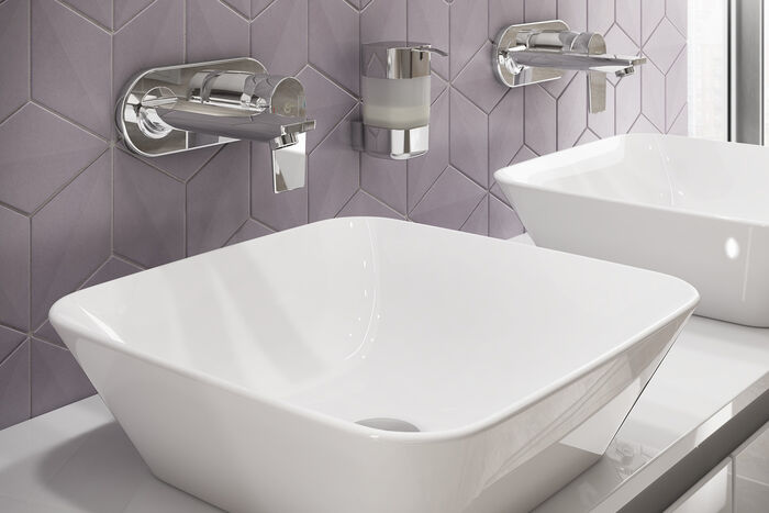 Viereckige Waschbecken mit Unterputzarmaturen an violetter beflieseter Wand.