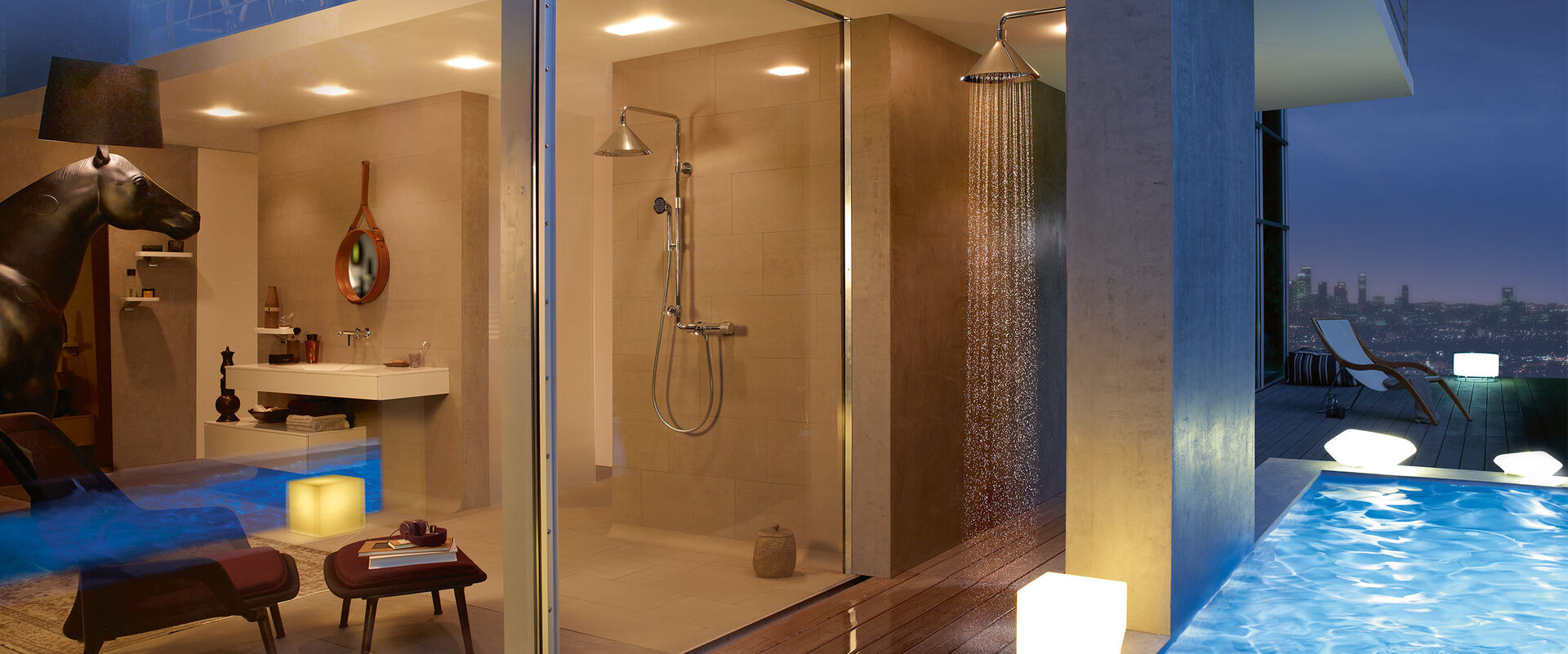 Penthouse-Wohnung mit Swimmingpool und Außendusche von AXOR ShowerProducts by Front auf dem Dach. Direkt daneben der Blick ins Badezimmer mit Dusche, ebenfalls von AXOR Showerproducts by Front. Im Badezimmer befindet sich außerdem eine Sitzgelegenheit, Waschbecken mit Spiegel und Dekoobjekte.