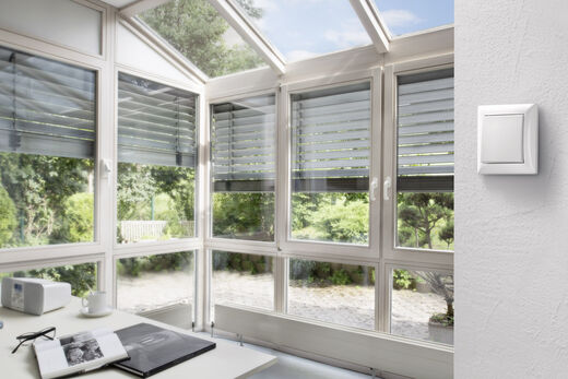 Smart Home von Bosch Wintergarten mit regulierbaren Jalousien halb geöffnet.