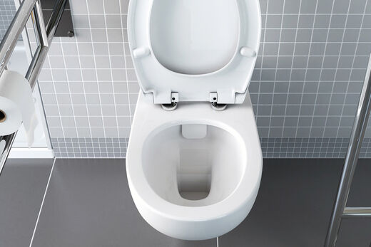 Spülrandloses WC von VitrA Conforma aufgeklappt mit Einsicht von oben vor grauen Fliesen. Mit Haltestange links.