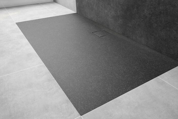 Schwarz-graue EasyFlat Duschfläche von HUEPPE, die in einem grau gefliestem Boden eingelassen ist.