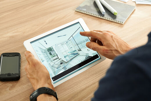 Männliche Hände halten ein iPad in der Hand, auf dem eine Badplanung zu sehen ist.