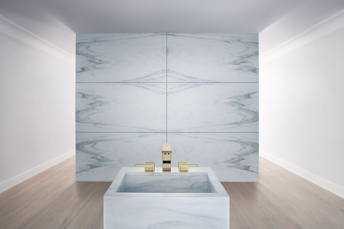 Puristische, eckige Badewanne aus Marmor mit einer bronze-farbenen Wannenrand-Armatur von AXOR Edge. 