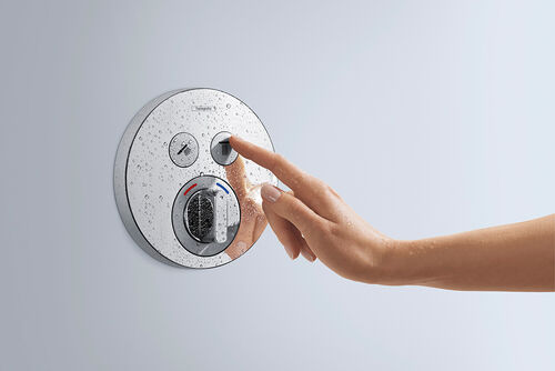 Shower Select Mixer von hansgrohe, in runder Form gehalten. Eine Hand betätigt den rechten Knopf des Thermostats.