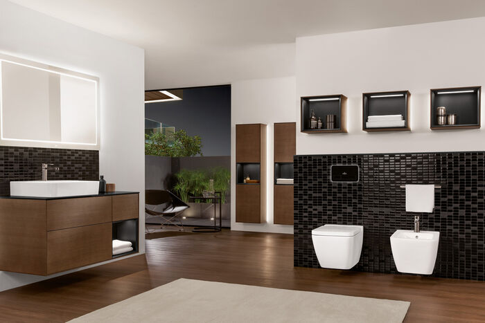 Exklusives Badezimmer mit brauenen Badmöbeln, Waschplatz, Badschränken und einer Toilette und Bidet.