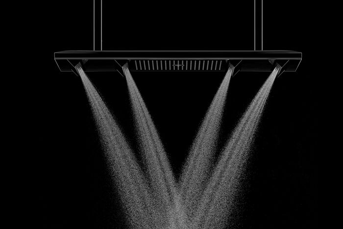 Design Duschsystem Shower Heaven von Axor. An einer rechteckigen, länglichen Kopfbrause sind mehrere zusätzliche Brausen quer über die eigentliche Brause installiert, aus denen in unterschiedliche Richtungen Wasser fließt.