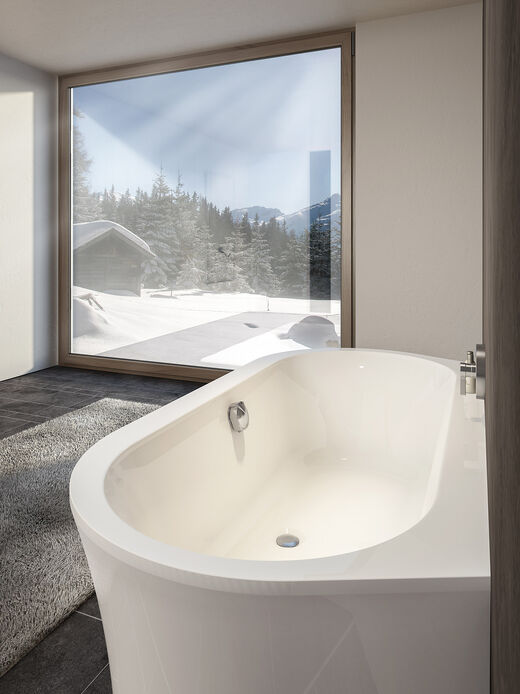 Ovale Badewanne an der Wand montiert mit Blick in eine Schneelandschaft.