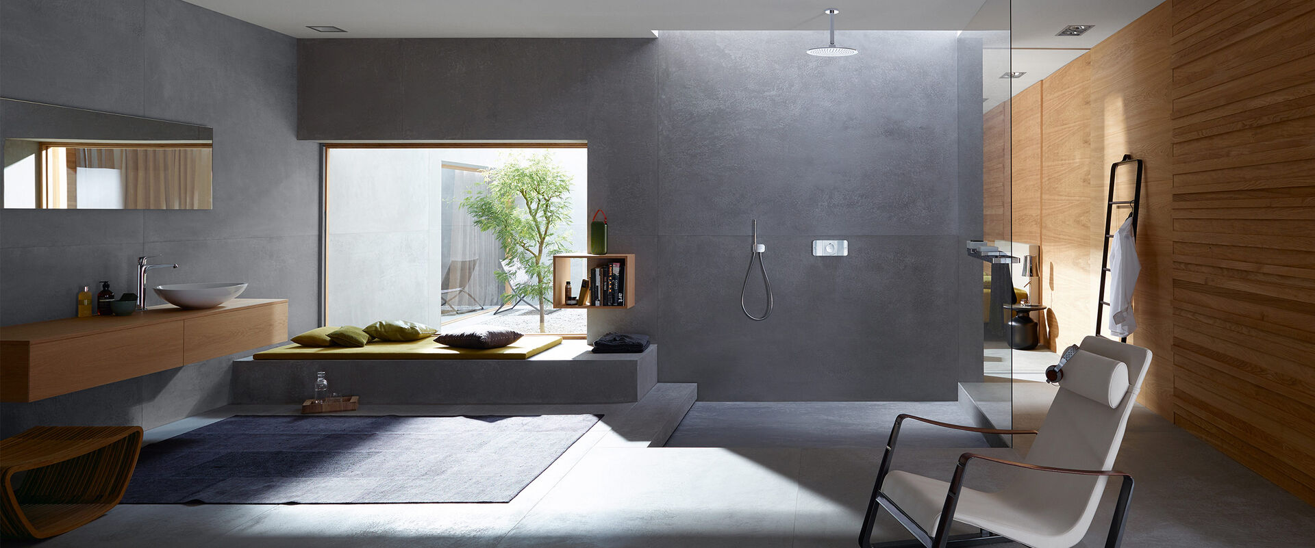 Badezimmerambiente mit Waschplatz und begehbarer Dusche mit Design Badarmatur. Sessel im Vordergrund.