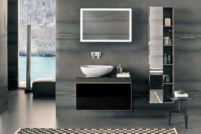 Blick auf Waschplatz mit Spiegelschrank beleuchtet, Aufsatzwaschbecken oval auf Badmöbeln aus Holz und einen Hochschrank mit Spiegel. 