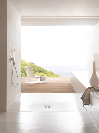 Design Badezimmer mit Terrasse und Ausblick im Hintergrund. Im Vordergrund ist eine Dusche installiert, auf dem Boden ist eine Bette AntiRutsch Duschfläche installiert. Rechts liegt ein Handtuch und ein Dekoobjekt.