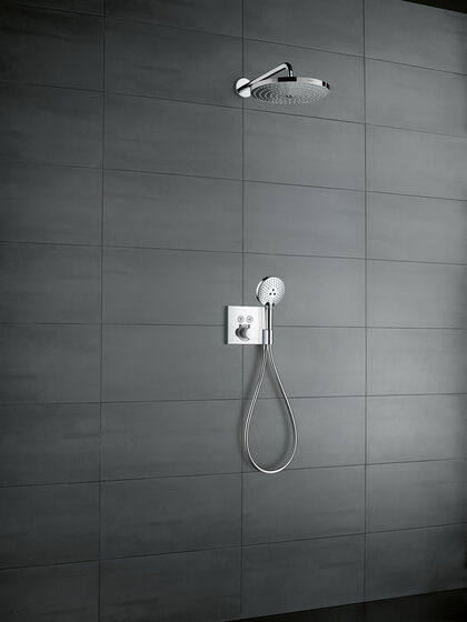 Grau geflieste Duschwand, an der ein rechteckiges hansgrohe ShowerSelect Thermostat befestigt ist. An diesem Thermostat befindet sich außerdem eine Handbrause mit Wasserschlauch. Darüber befindet sich eine Kopfbrause.