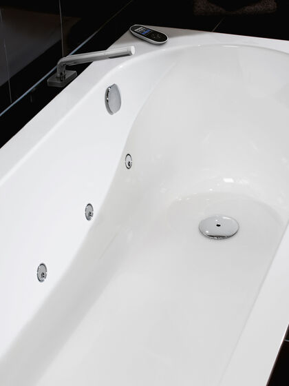 Weisse Badewanne mit Whirlsystem und Fernbedienung.